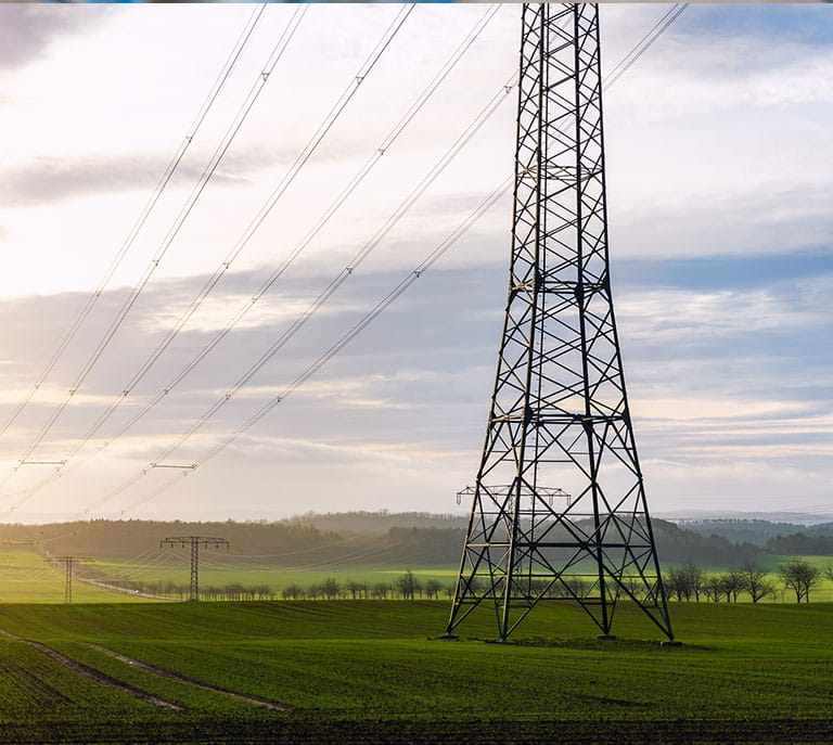 a large green field with trees in the background with Tees Transporter Bridge in the background